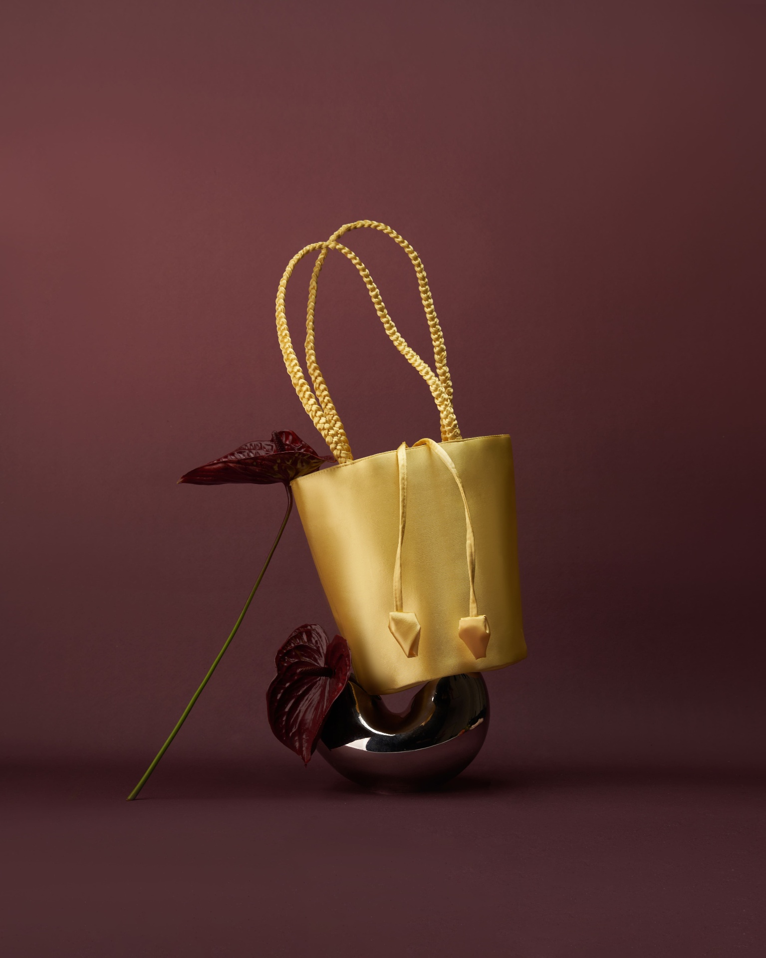 Butter yellow satin bucket bag with anthurium on burgundy backdrop