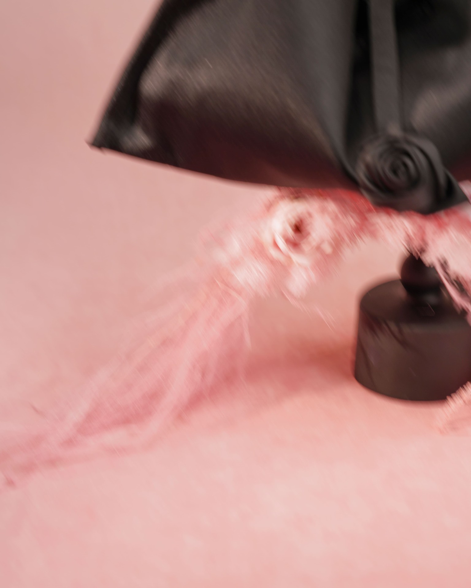 Black satin shoulder bag with rose in motion blur