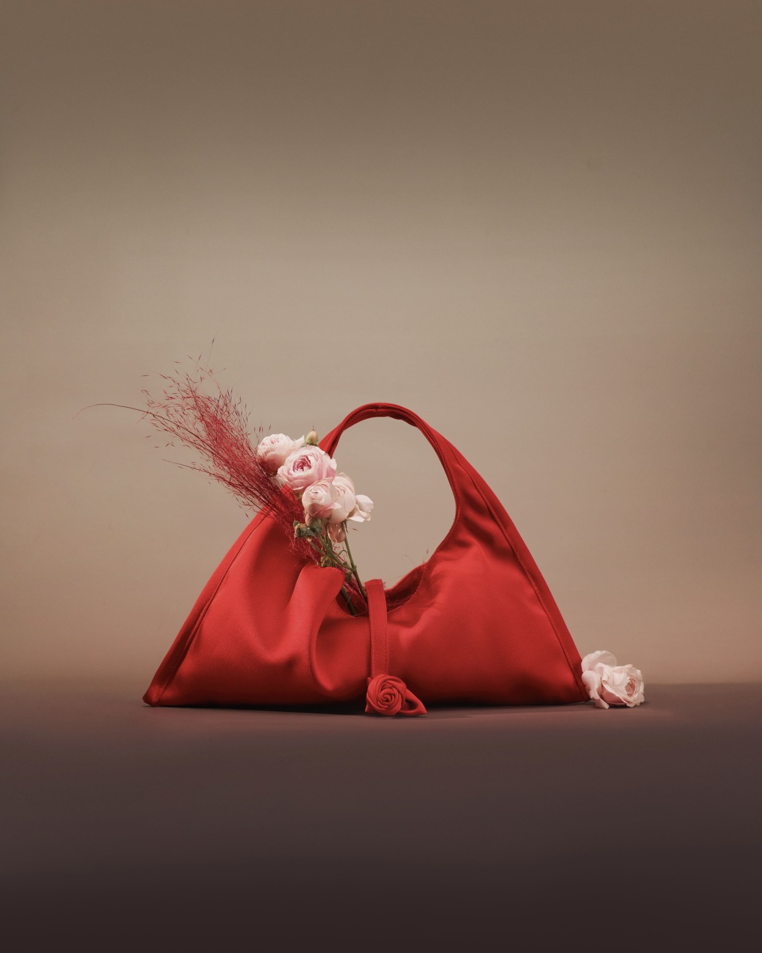 Red satin shoulder bag with pink roses still life